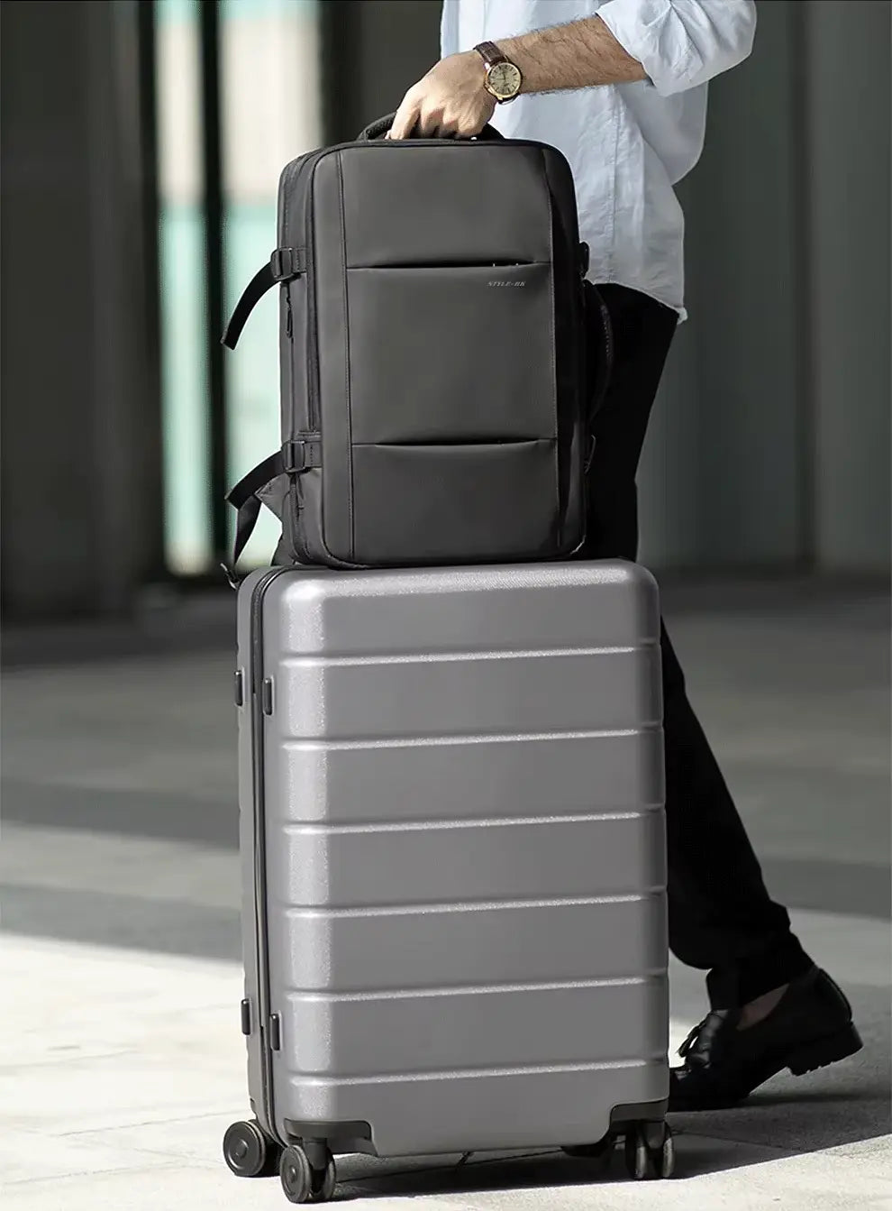 Black expandable backpack carried with rolling luggage